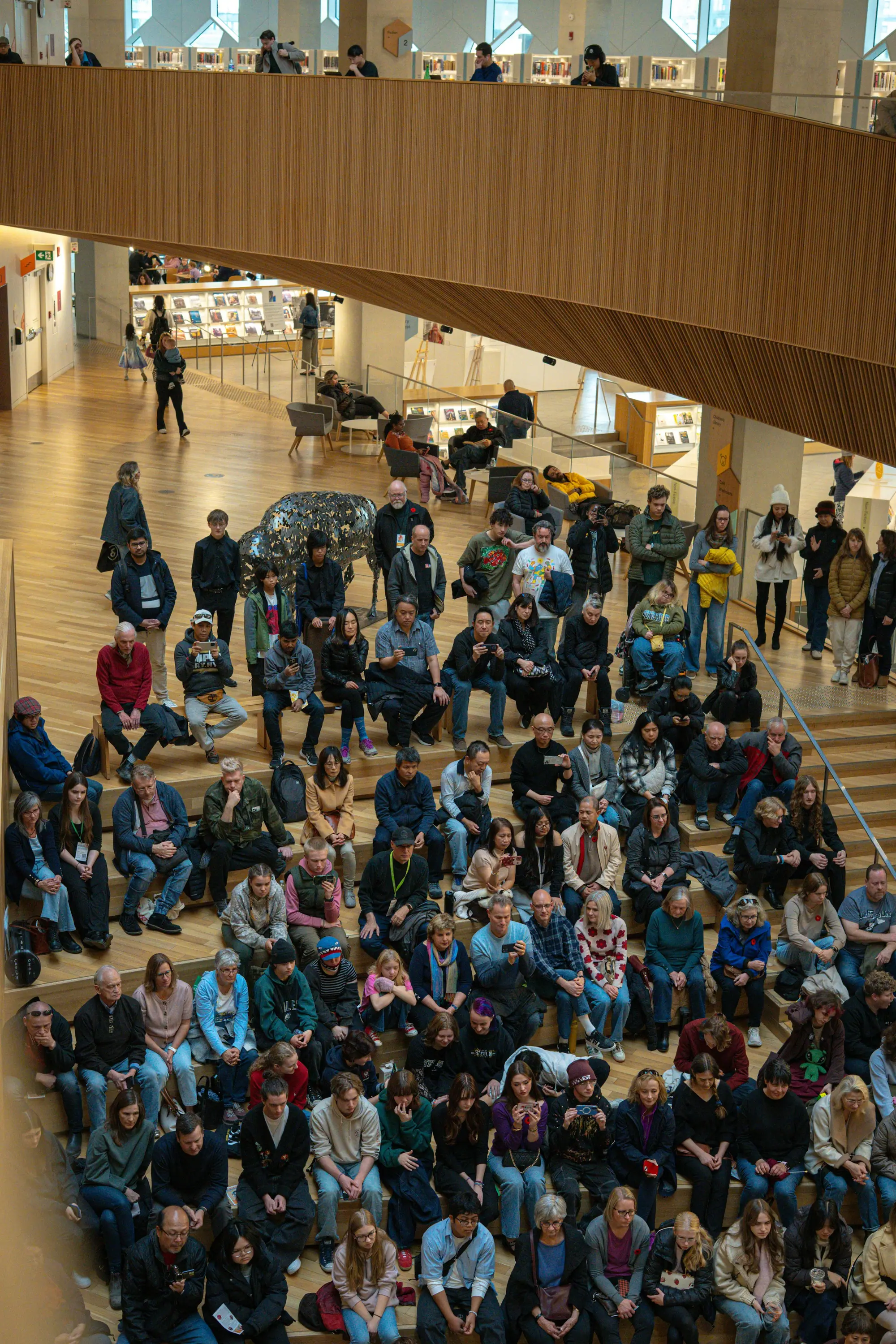 Large crowd seated on wide wooden stairs at a community event